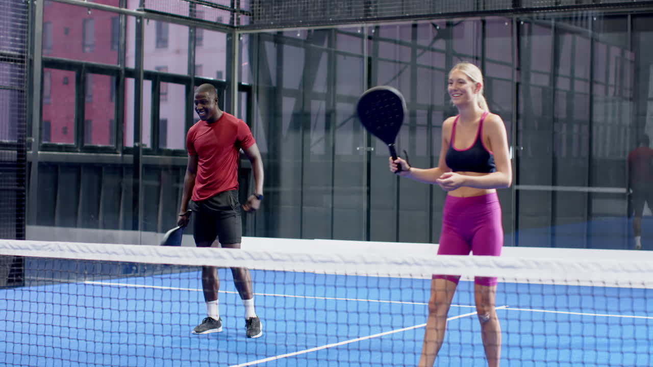 African American man playing padel tennis on blue indoor court, focused on game