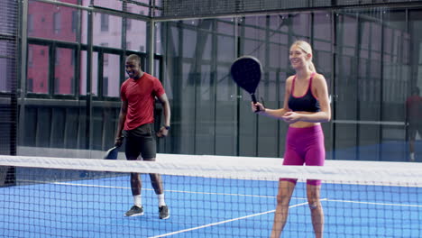 african american man playing padel tennis on blue indoor court, focused on game