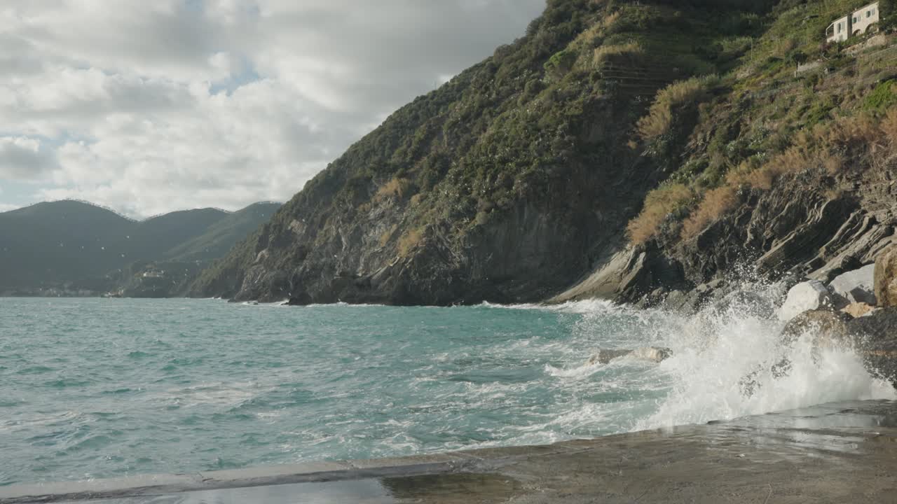 Onde agitate che si infrangono e schizzano sulle rocce e sul porto in estate