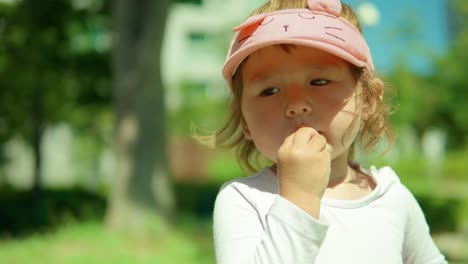 young adorable toddler girl eating snacks at the outdoor playground