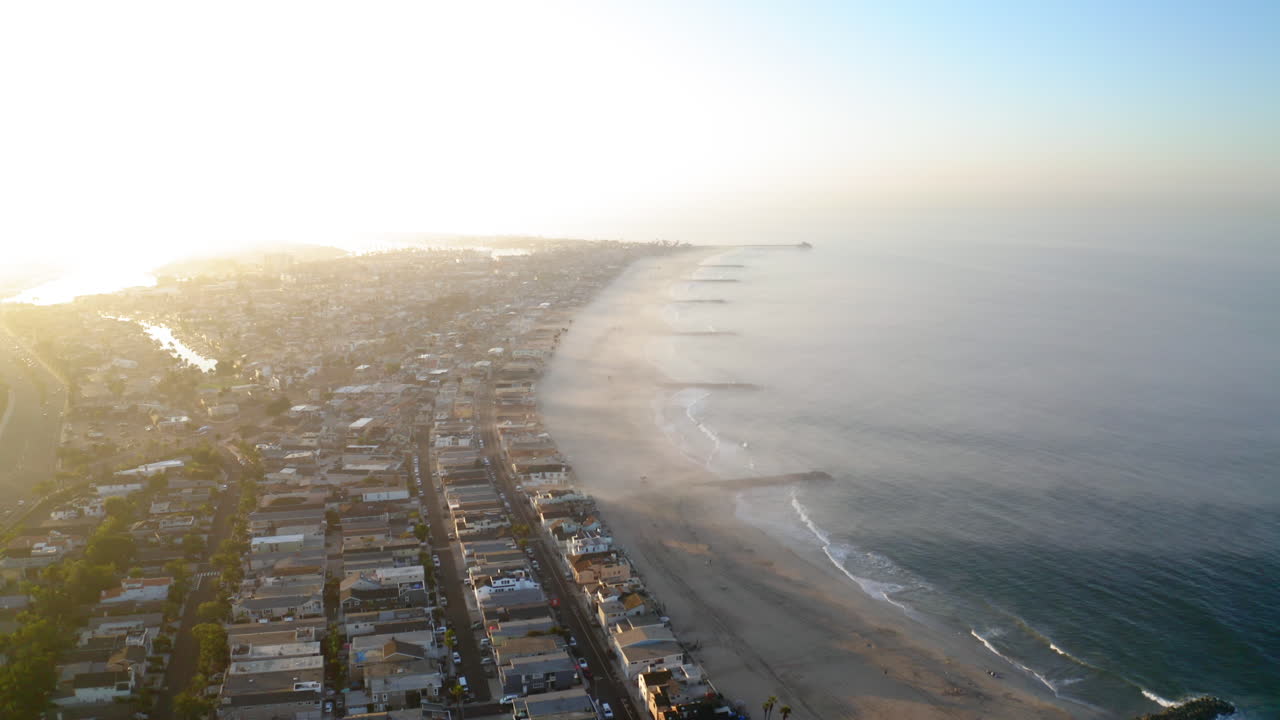 Vista aerea di una città costiera e spiaggia con foschia sull'oceano all'alba