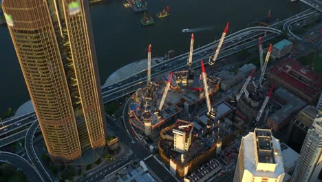 view from above of multiple tower cranes at construction development site along riverside expressway