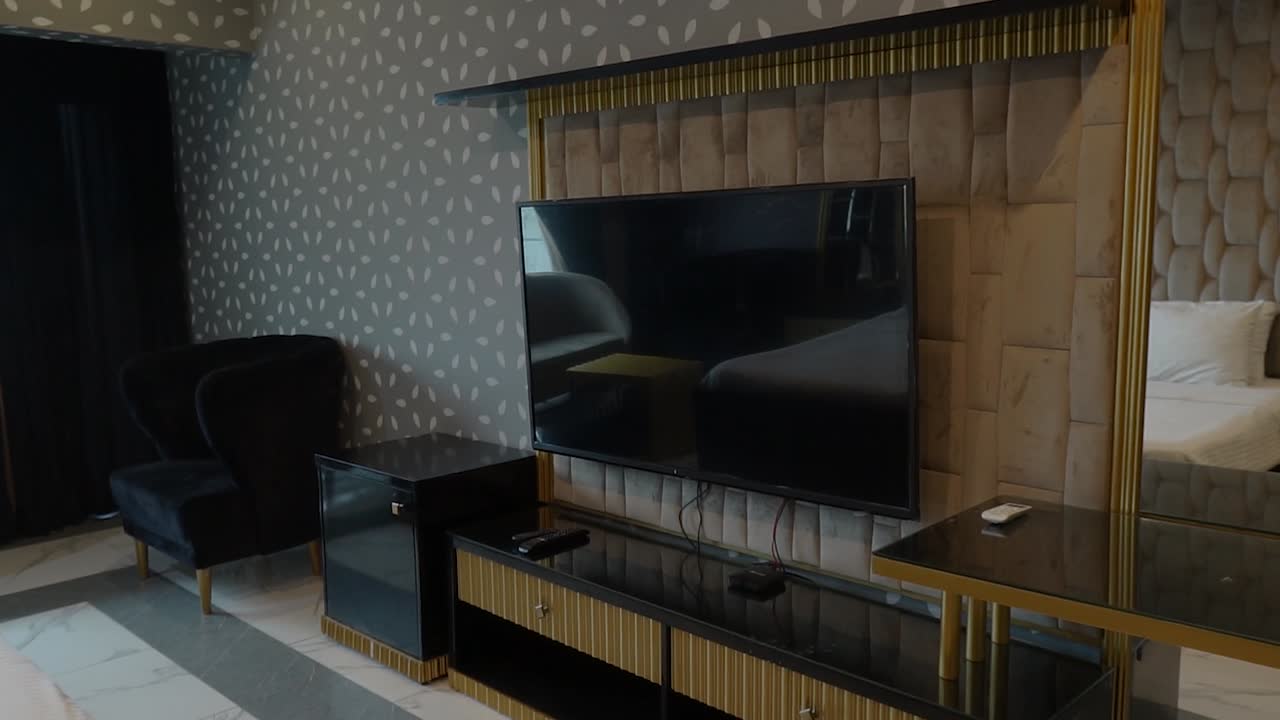 Pan Left View Inside Modern Upmarket Bedroom With Hanging Flat Screen On Wall