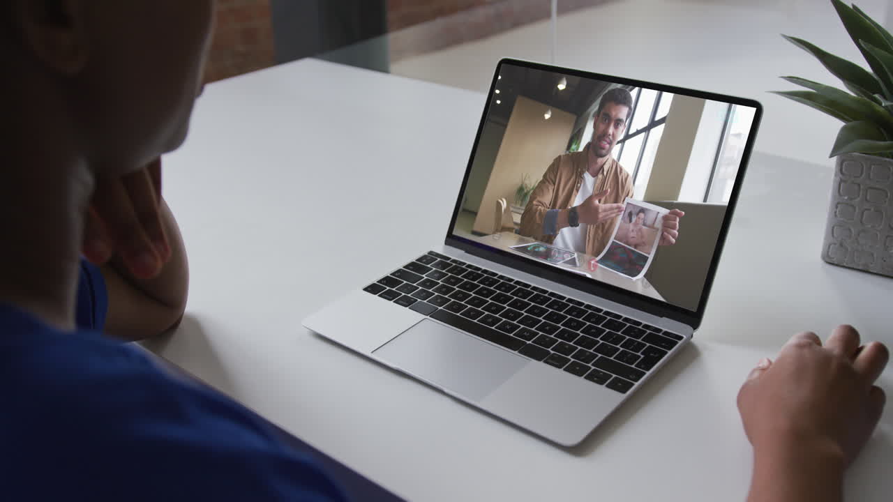 Mid section of african american woman having a video call with male colleague on laptop at office