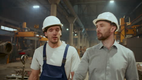 engineer and technician walking through industrial plant and talking