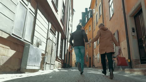 un couple heureux qui court le long d'une rue étroite.