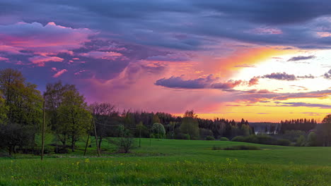 clouds passing by in timelapse on the sunset sky over a beautiful rural green field landscape with yellow flowers