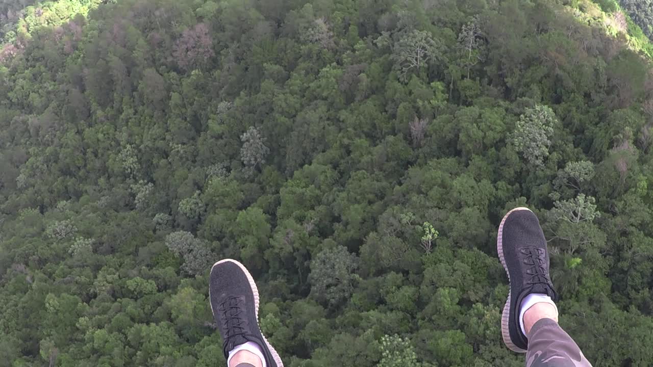 Paraglyder looking down flying high with the wind and the blue sky with more paraglyders, enjoying a caribbean mountain view in the Dominican Republic. Looks almost like he is dreaming and flying