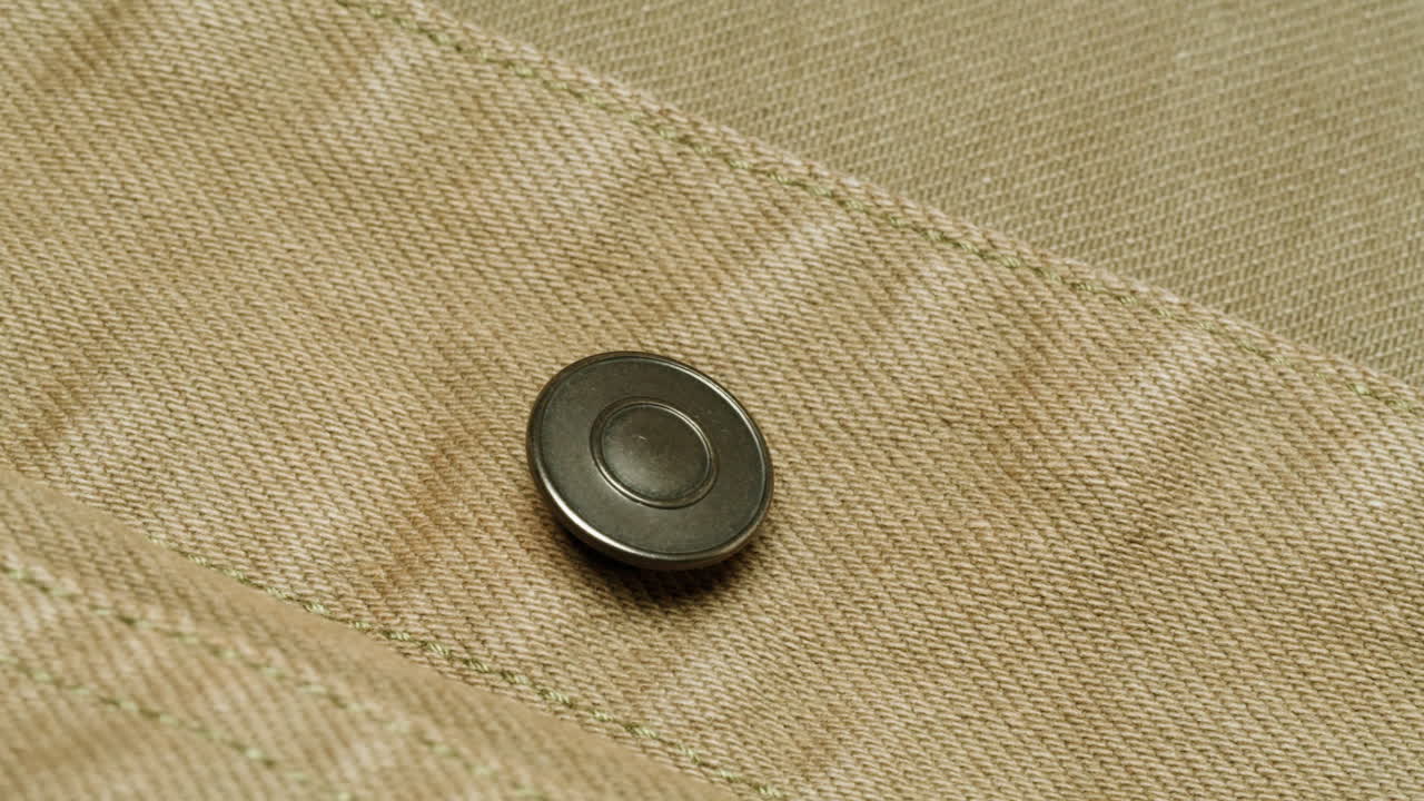 Nærbilde av en beige dongerijakkeknapp
