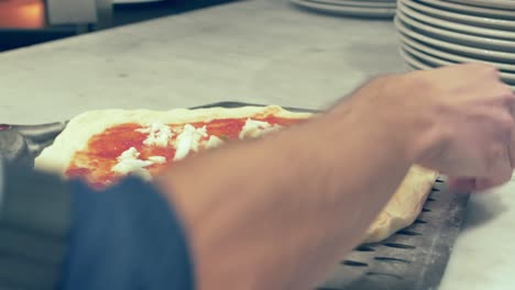 cook placing the pizza in the pizza peel before putting it inside the oven