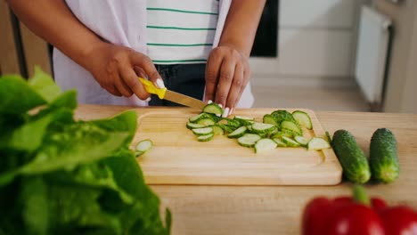 woman chopping cucumbers in kitchen