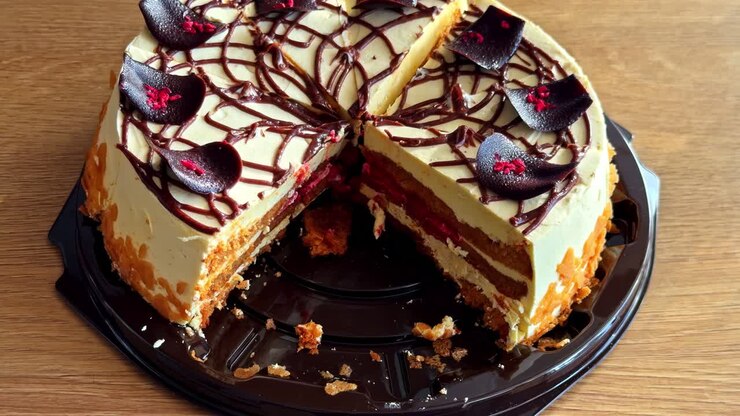 Bolo de chocolate e creme em camadas com recheio de frutas vermelhas, parcialmente fatiado em bandeja de servir.