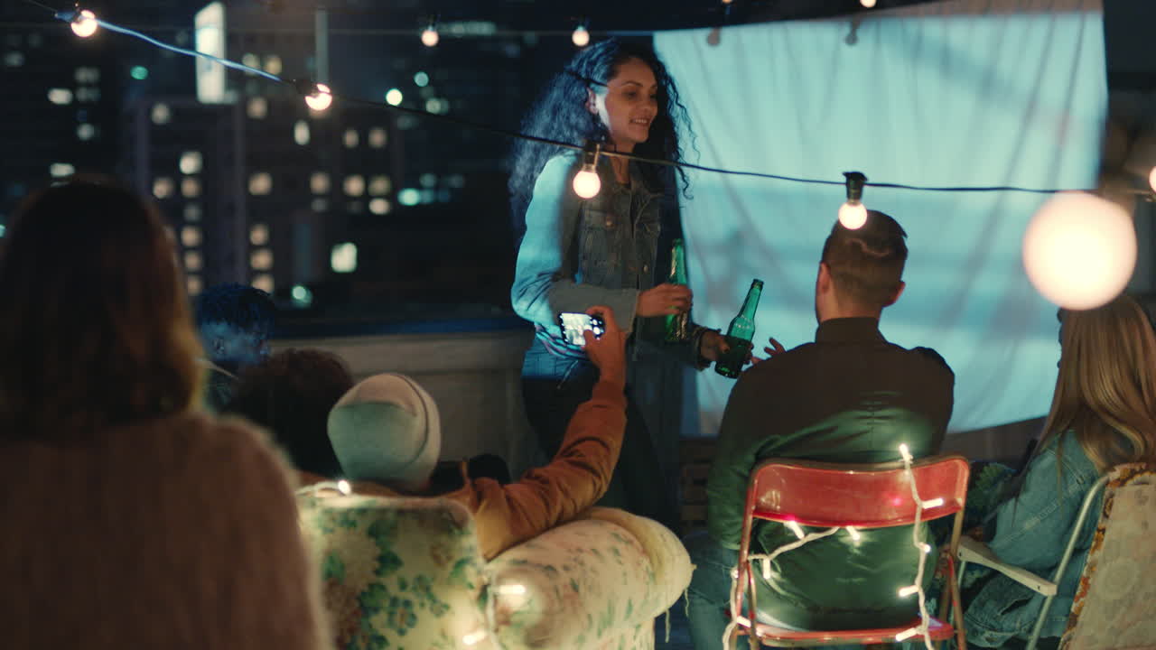 다양한 친구 들 의 그룹 이 옥상 영화관 에서 영화 를 보고 함께 어울려서 도시 의 저녁 에 주말 재회 파티 를 즐기고 있다