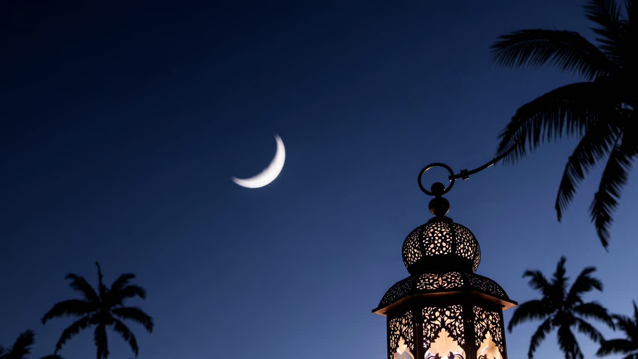 Silhouetted lantern against a crescent moon and palm trees at dusk, captured from a low angle