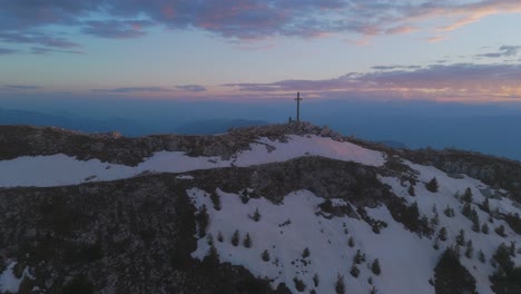 corno bianco mountain at sunset with patches of snow and a cross on the summit, aerial view