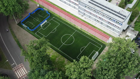 Toma-Aérea-Hacia-Atrás-De-Un-Nuevo-Campo-De-Fútbol-Y-Pista-De-Atletismo-Al-Lado-De-La-Escuela-Primaria-En-Polonia,-Dron-De-4k