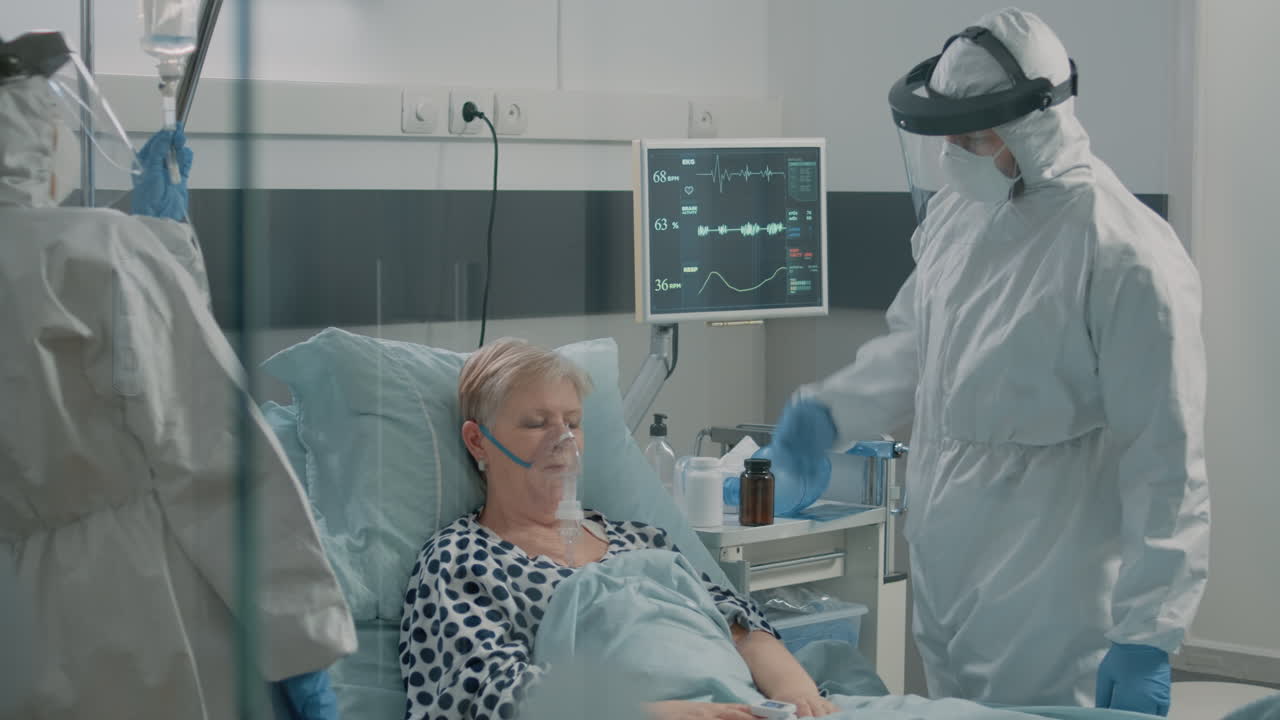 Medical staff in hazmat suits consulting aged patient