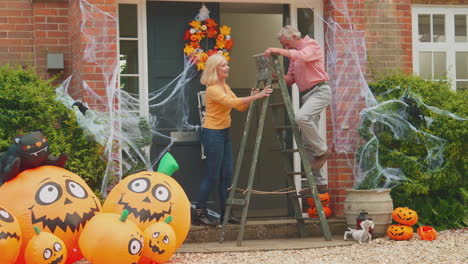 grandparents at home putting up halloween decorations for trick or treat