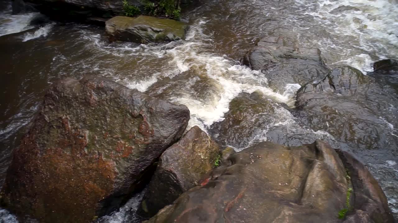Filmato di un piccolo fiume che scorre attraverso la grande roccia