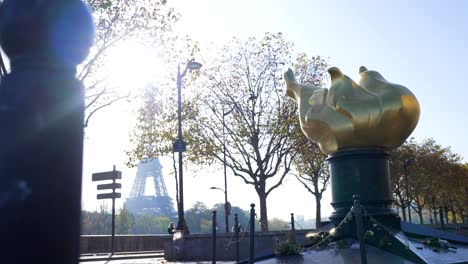 golden olympic flame statue in paris with eiffel tower in the background, in bright sunlight, in slow motion
