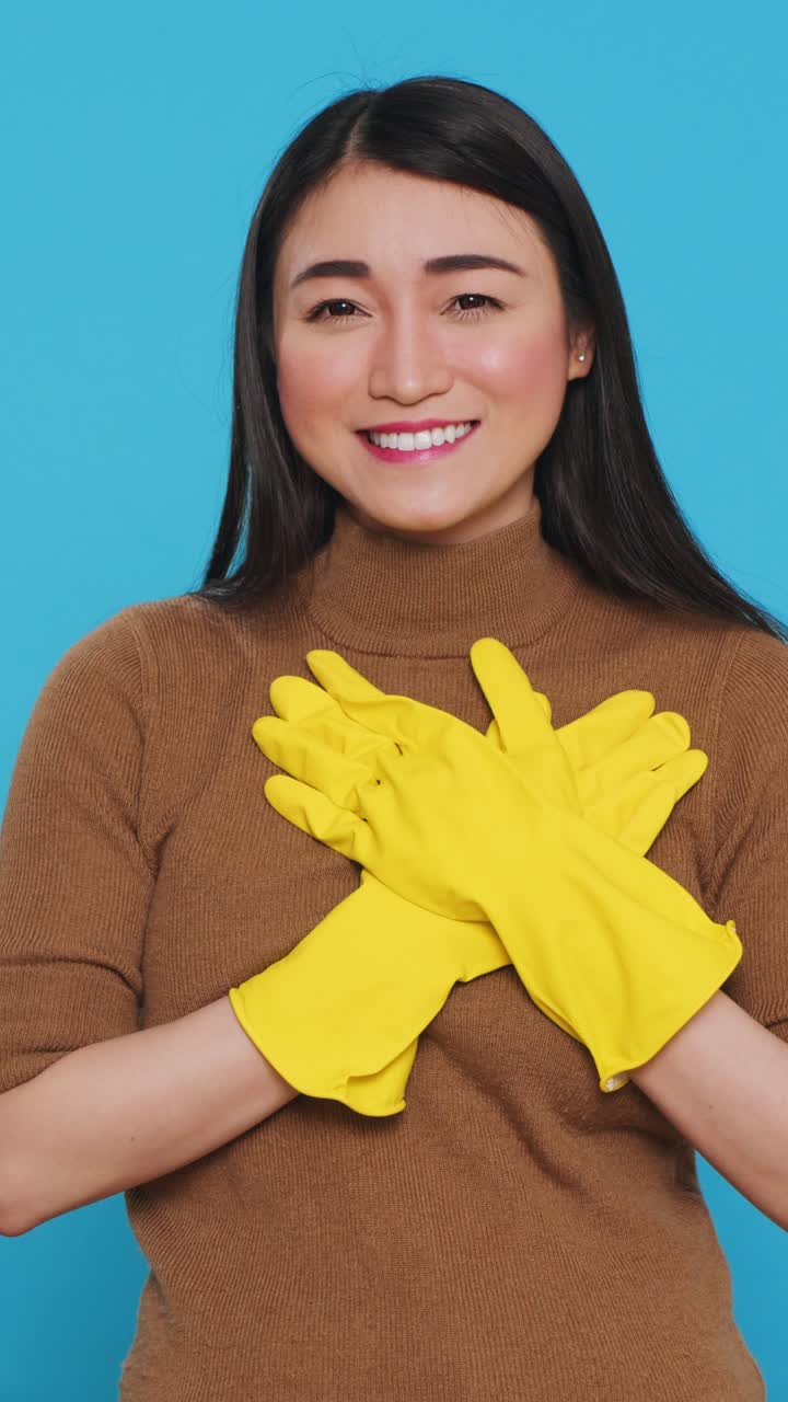 Vertical video: Smiling asian maid clapping hands in front of camera after finishing to do house cleaning
