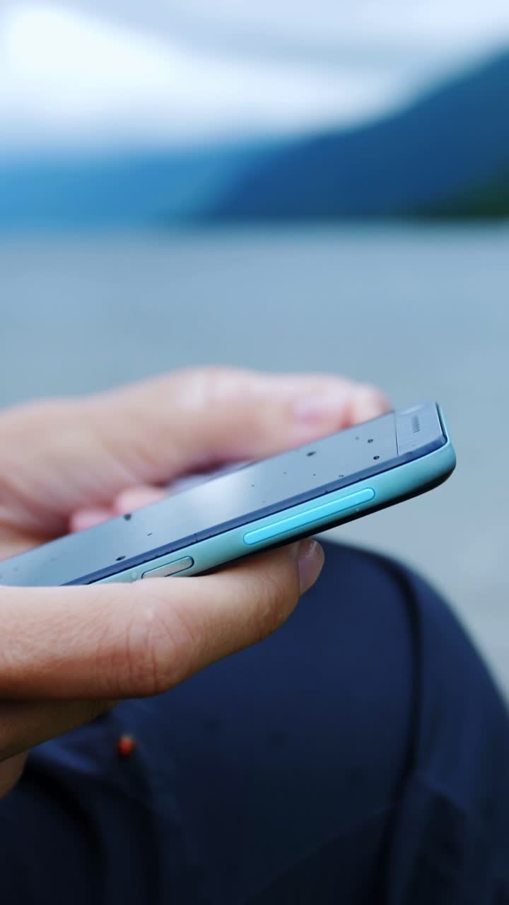 Person using a mobile phone to make a payment near a lake
