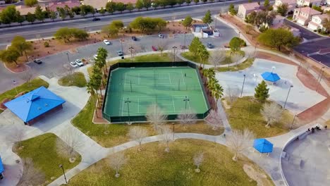 Aerial-view-kids-riding-bikes-at-park,-playing-tennis-in-neighborhood-park