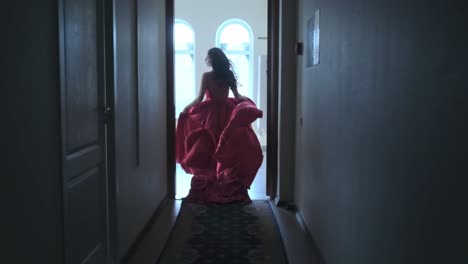 woman in red gown walking through a hallway