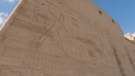 view of ancient egyptian hieroglyphs carved into the wall in temple medinet habu, luxor