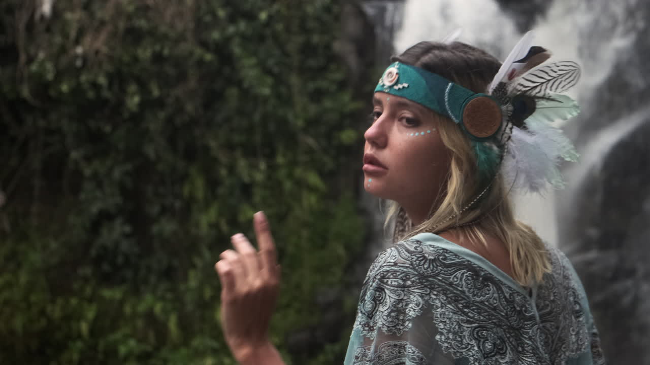 Woman in a Boho Headdress near a Waterfall