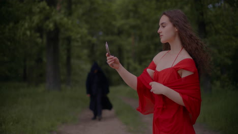 woman in red dress and reaper in forest