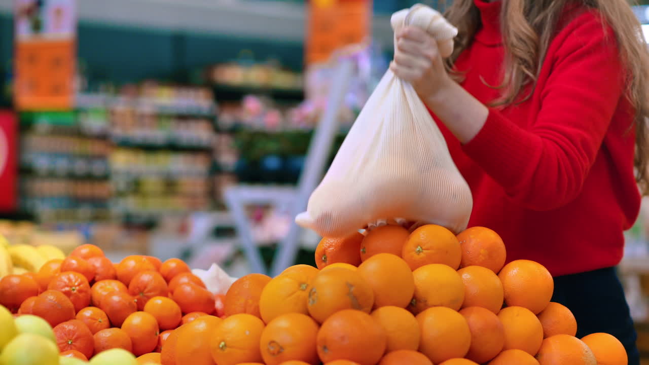 Donna che raccoglie arance in una borsa riutilizzabile in un negozio. Tematiche relative all'ecologia e alla Giornata della Terra