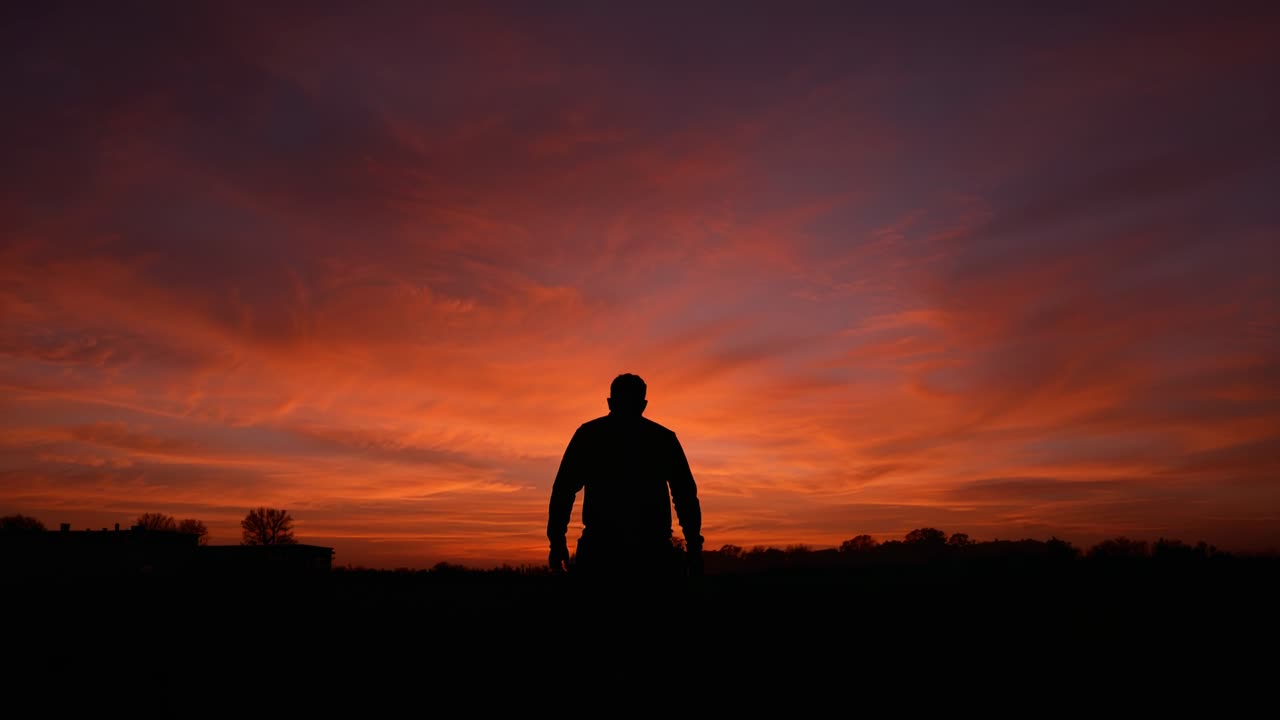Moving man silhouette edging forward as sunset drawing him at horizon ...