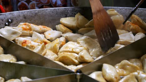 street food. chef cooking polish dish - pierogi, frying them in hot oil in a large skillet