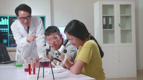 young asian boy and girl learning science experiment in laboratory with teacher in classroom, teacher explain with laptop computer