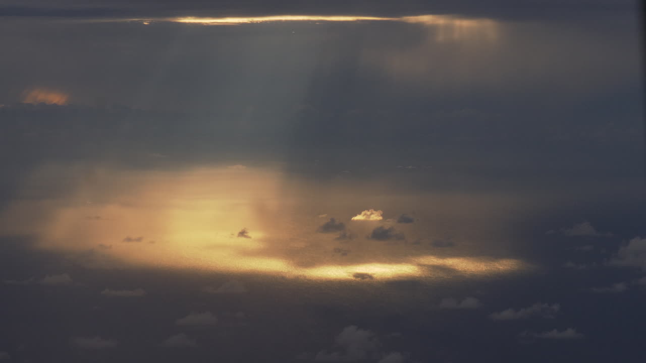 Aerial view from airplane of sun rays shining through dramatic clouds.