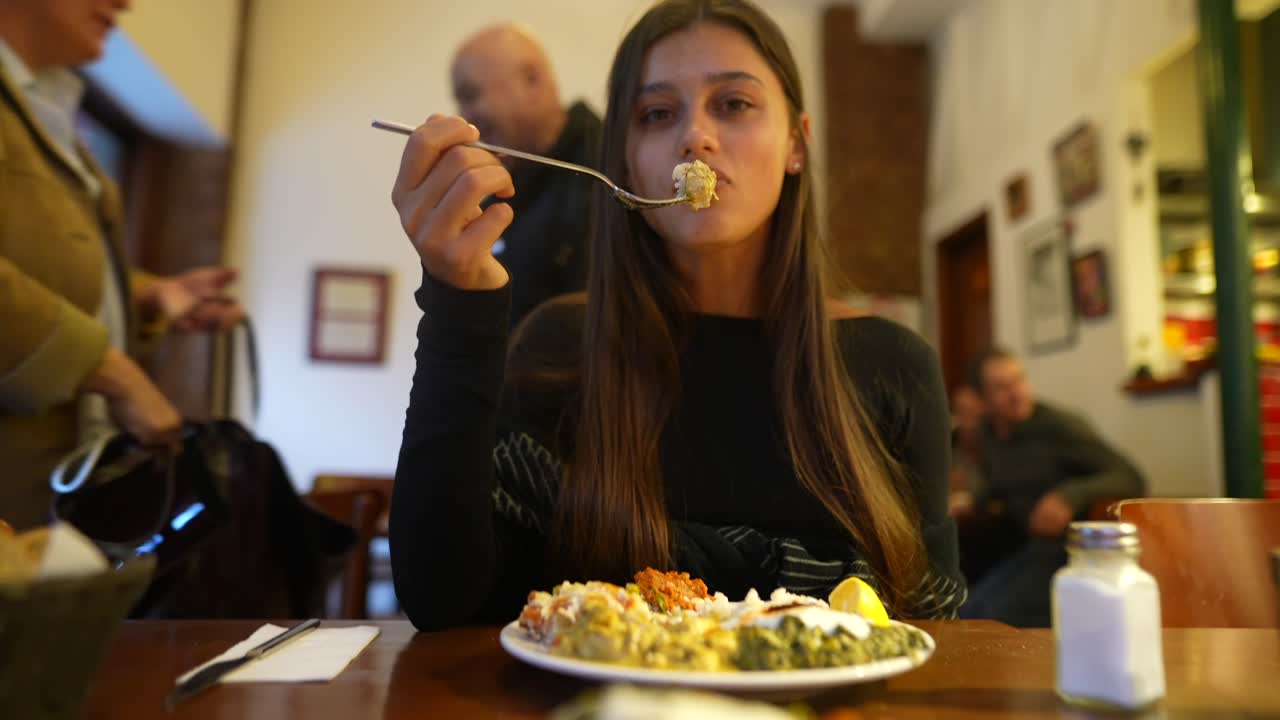 una mujer joven comiendo en un restaurante.