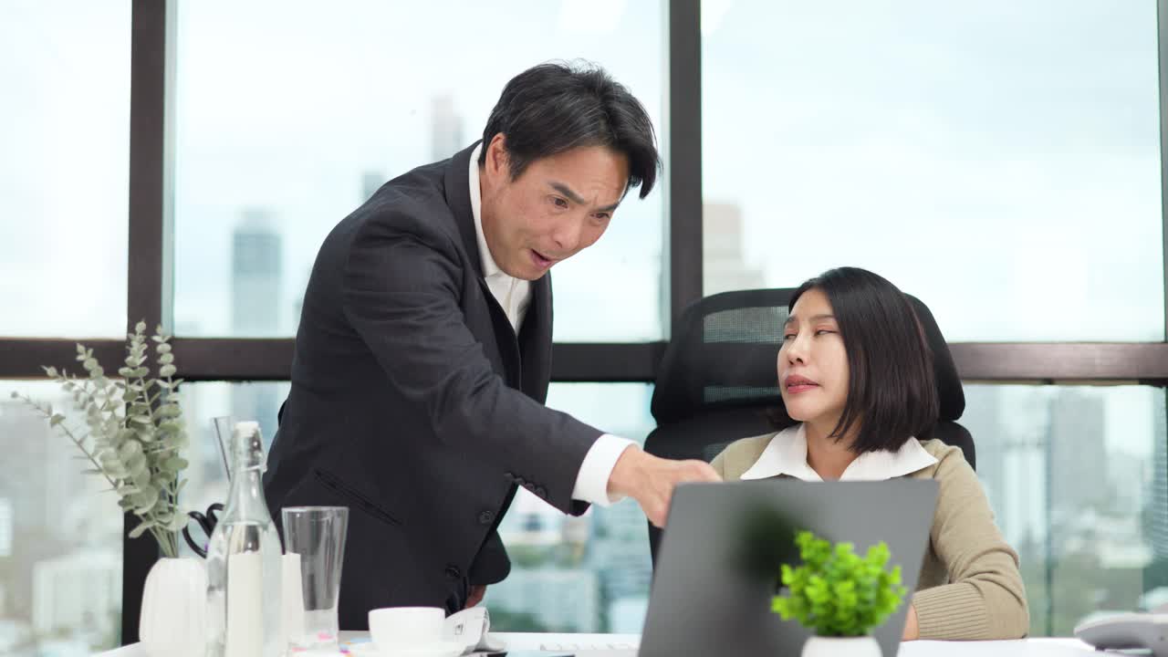 ผู้เชี่ยวชาญสองคนมีส่วนร่วมในการตรวจสอบเอกสารที่ตึงเครียดที่โต๊ะท างานในส านักงานที่สว่างสดใสพร้อมวิวเมือง