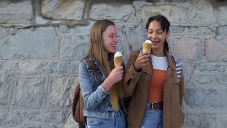 Vista-Lateral-De-Una-Chica-Caucásica-Y-De-Raza-Mixta-Comiendo-Helado-Junto-Al-Mar