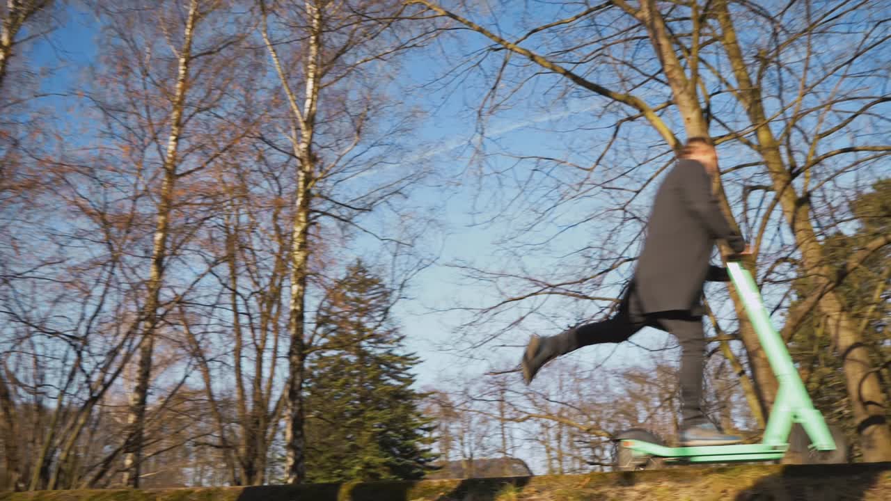 도시 공원의 아침 분위기를 통해 전기 스쿠터를 타고 즐기는 우아한 옷을 입은 남자