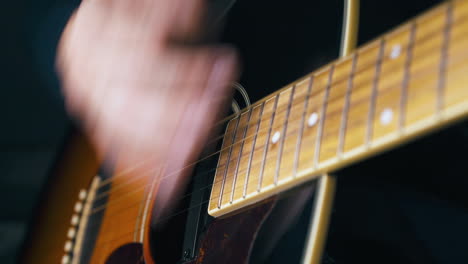 delighted person plays acoustic guitar with hand closeup