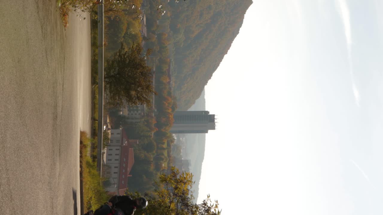 Brand new red sporty scooter driving uphill in mountain road in Banska Bystrica, a town in Central Slovakia - vertical establishing shot