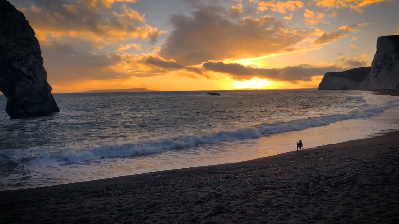 una fascinante vista de la puesta de sol en durdle door, dorset, inglaterra, que muestra un arco de piedra caliza natural y un océano en calma en el fondo