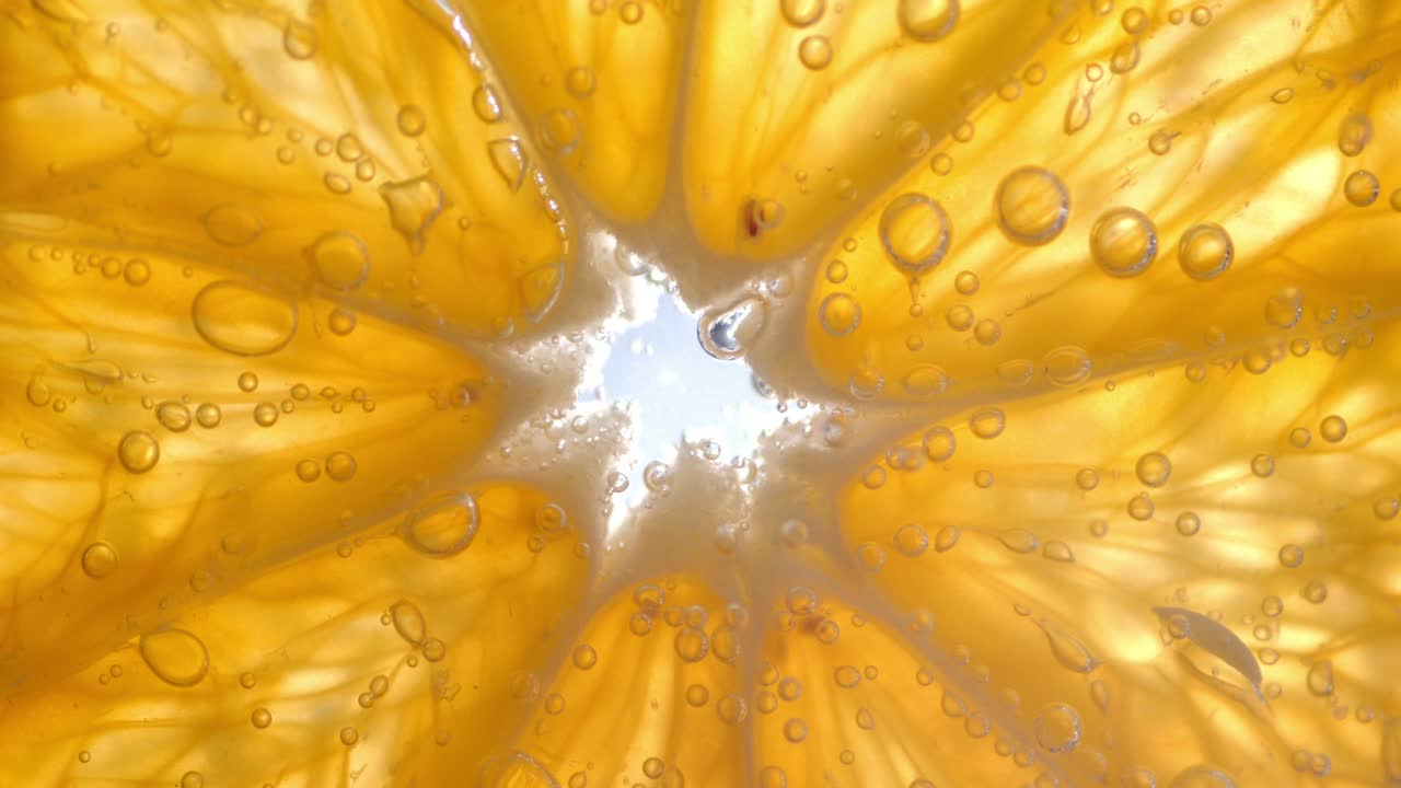 Slice of Mandarin under water with air bubbles.