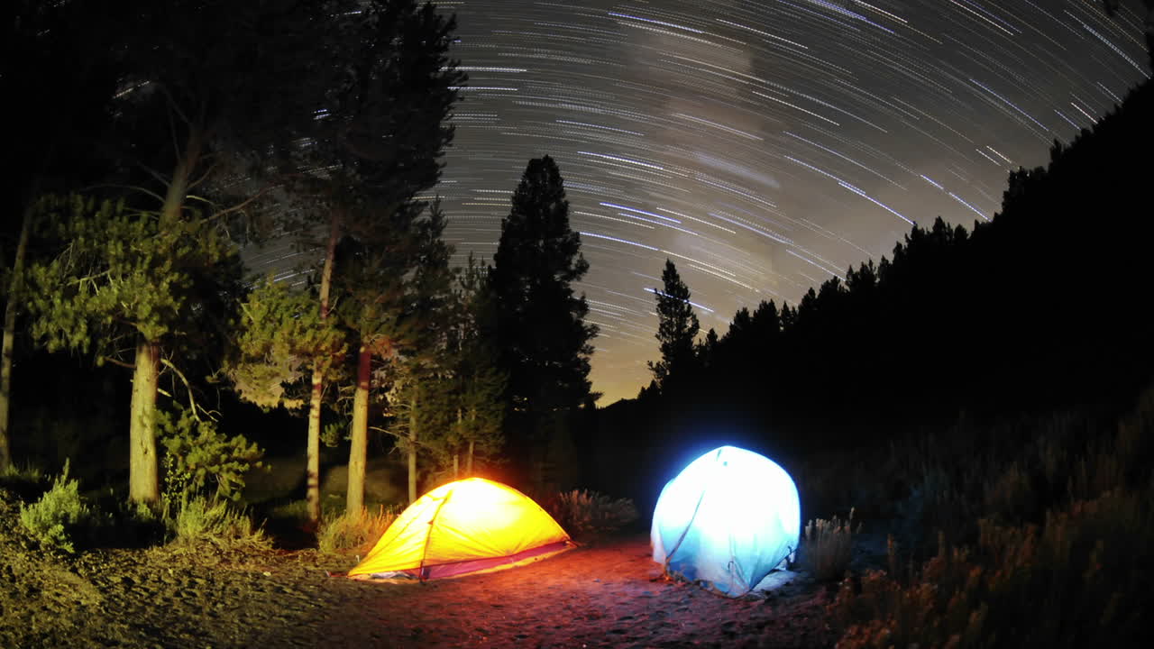 캘리포니아 컨빌 근처의 세쿼이아 국유림에 있는 큰 초원에 있는 두 개의 라이트 텐트 위에 저속 스타 트레일 줄무늬