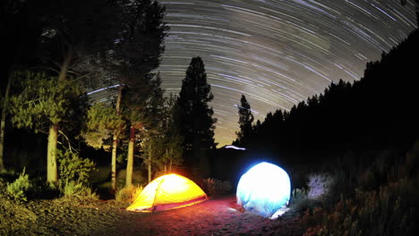 time lapse star trail streaks over two lite tents in big meadow in sequoia national forest near kernville california