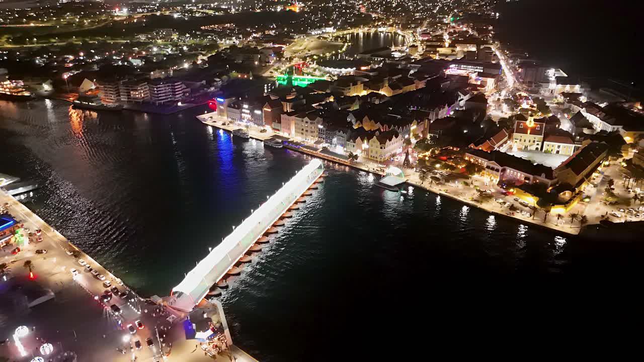 Pontoon bridge of Handelskade Willemstad Curacao shines bright in the evening, aerial