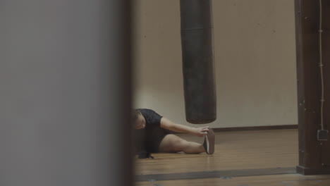 Slider-shot-of-young-woman-stretching-legs-in-gym-before-workout