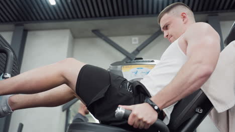 fitness freak pushing heavy weight on leg press machine under bright gym lights with focused determined expression showing controlled intense lower body workout form and muscle engagement