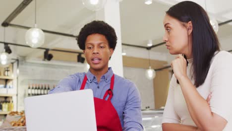 Video-of-diverse-female-owner-and-male-waiter-working-with-laptop-at-cafe-shop